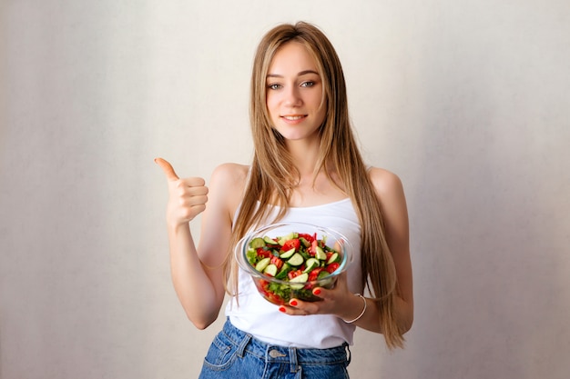 junges gesundes Mädchen mit einer Tasse Gemüsesalat