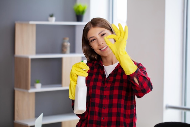 Junges glückliches Dienstmädchen, das das Büro putzt