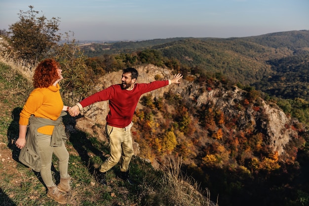 Junges glückliches lächelndes Paar in Liebe, das Wochenende in der Natur verbringt. Paar, das Hände hält und schöne Natur an einem sonnigen Herbsttag genießt.