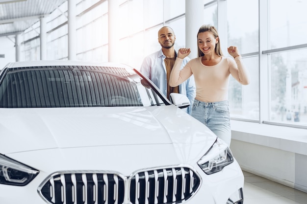 Junges glückliches Paar, das ein neues Auto im Autohaus wählt