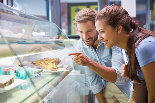 Junges glückliches Paar, das Kuchen wählt