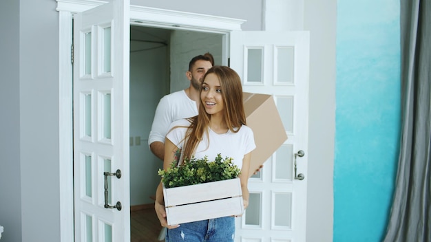 Junges glückliches Paar, das nach dem Umzug in ein neues Haus geht