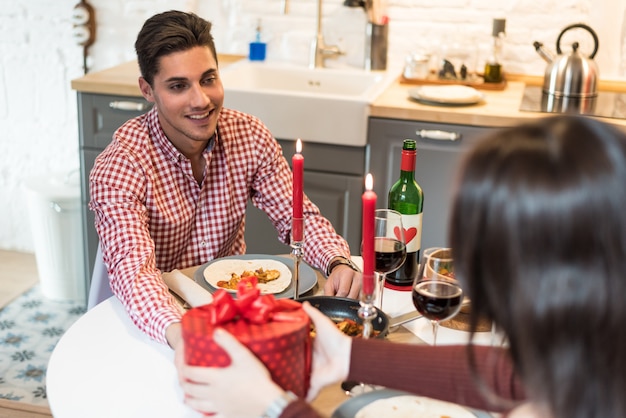 Junges glückliches Paar, das Valentinstag mit einem Abendessen zu Hause trinkt Wein, Beifall feiert.