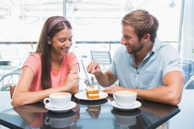 Junges glückliches Paar, das zusammen Kuchen isst