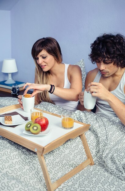 Junges glückliches Paar in der Liebe beim Frühstück im Bett serviert über einem Tablett zu Hause. Paar zu Hause Lifestyle-Konzept.