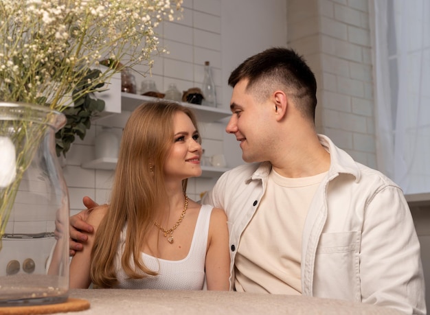 Junges glückliches Paar lächelt und schaut zärtlich auf die Augen, schöne Frau und gutaussehender Mann sitzen an