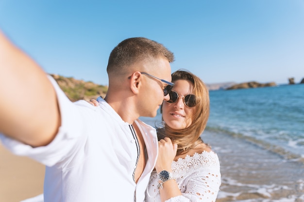 Junges glückliches Paar macht Selfie am Strand