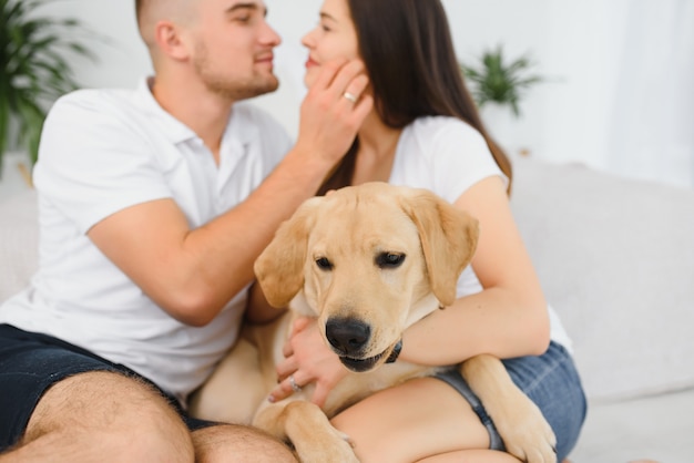 Junges glückliches Paar mit Hund, der zu Hause sitzt