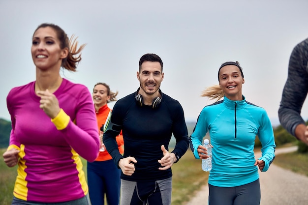 Junges glückliches sportliches Paar, das einen Marathon in der Natur läuft