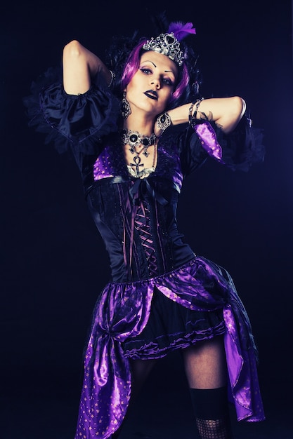 Junges Gothic-Mädchen, das eine seltsame Kleidung in Violetttönen anzieht