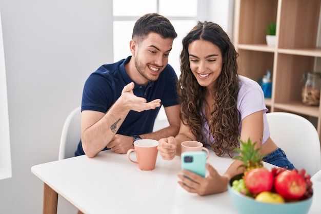 Junges hispanisches Paar trinkt Kaffee und führt zu Hause einen Videoanruf