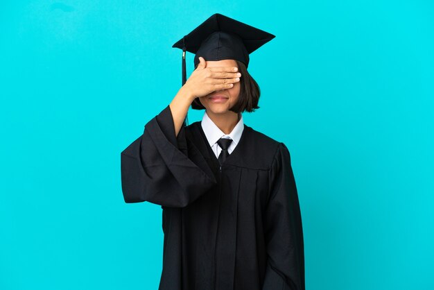 Junges Hochschulabsolventenmädchen über lokalisiertem blauem Hintergrund, der die Augen mit den Händen bedeckt. Will etwas nicht sehen