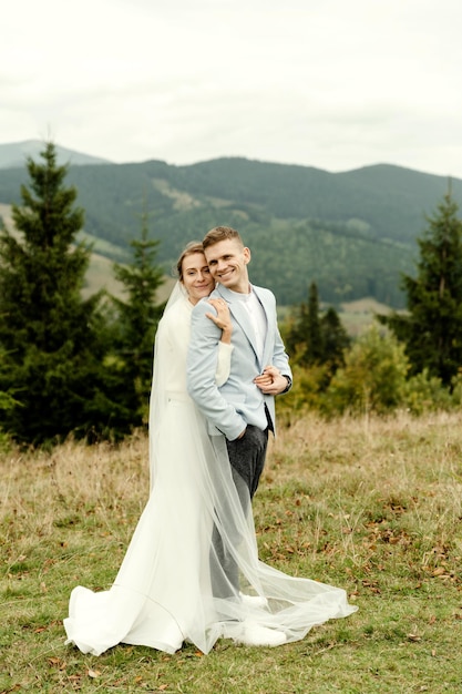 Junges Hochzeitspaar, das sich nach der Hochzeitszeremonie in den Bergen sanft umarmt, schöner Hochzeitstag