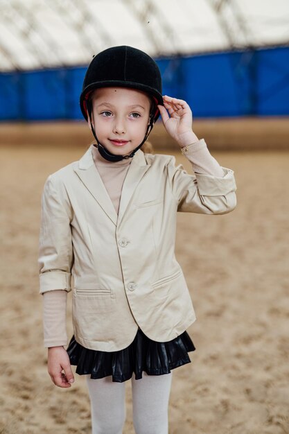 Junges hübsches kind mit jockeyhelm nettes mädchen im jockeytragen