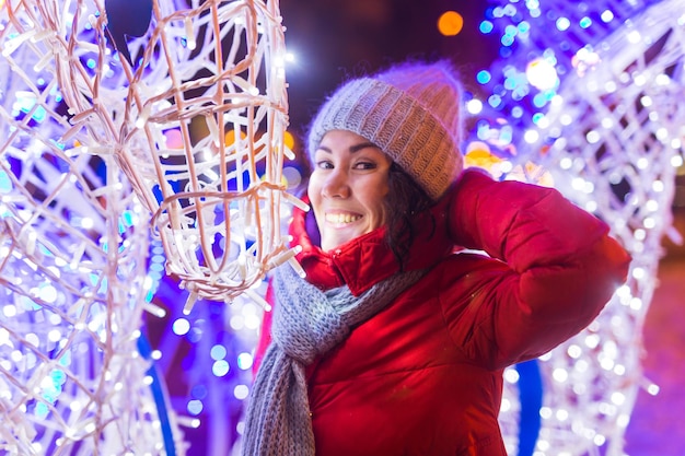 Junges hübsches lustiges Mädchen, das Spaß im Freien im Winterweihnachtsstadt- und Winterferienkonzept hat