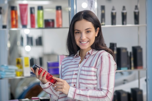 Junges hübsches Mädchen, das eine Flasche mit Haarspülung hält