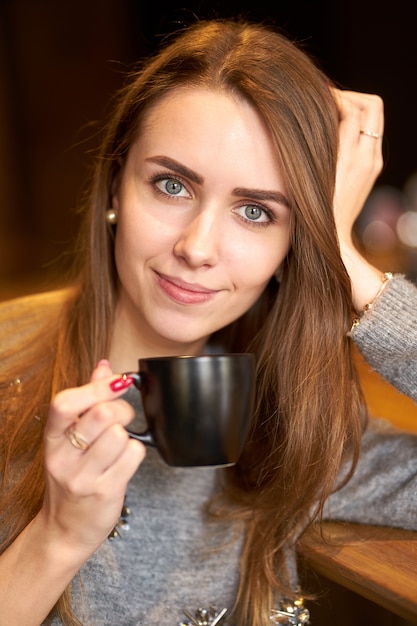 Junges hübsches Mädchen mit langen Haaren, die Kaffee oder Tee im Café trinken.