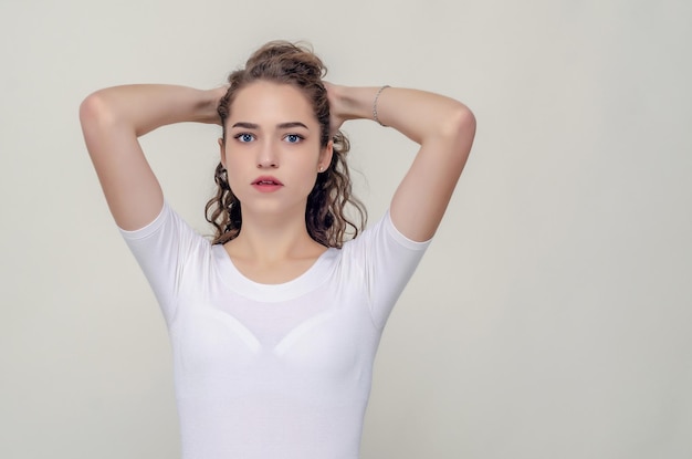 Junges hübsches Mädchen sammelte Haare hinter Ellbogen nach vorne, Hände hinter dem Kopf