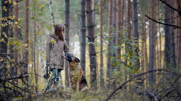 Junges hübsches weibliches Model, das mit ihrem Haustier spielt - Deutscher Schäferhund - Wandern auf einem Herbstwald - Mädchen wirft dem Hund einen Stock, Tele