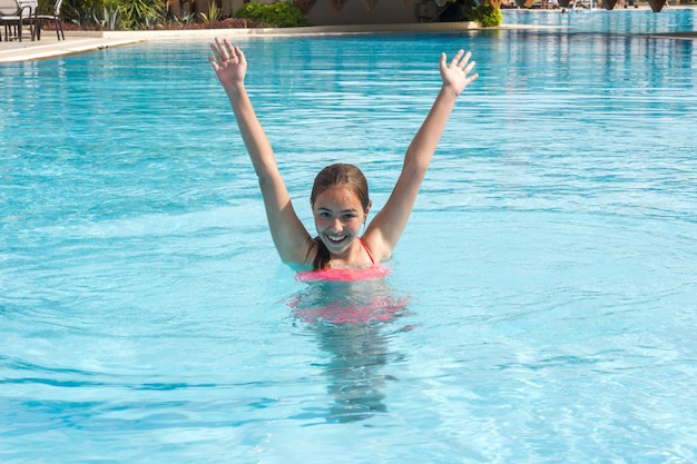 Junges jugendlich Mädchen schwimmt und hat Spaß im Außenpool