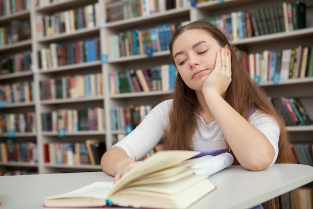 Junges junges Mädchen, das an der Bibliothek studiert