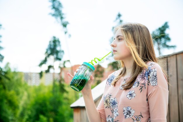 Junges kaukasisches Mädchen genießt die Sonne und trinkt Smoothies