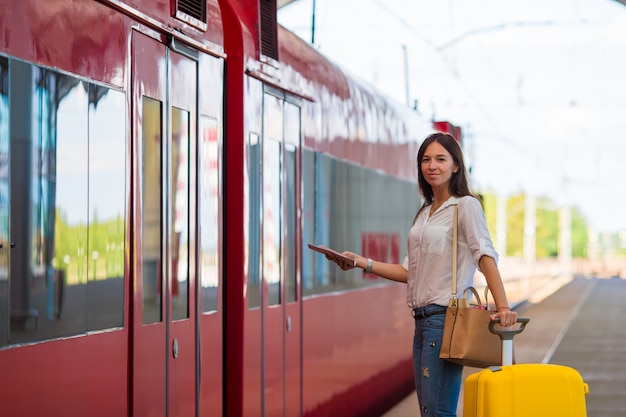 Junges kaukasisches Mädchen mit Gepäck an der Station, die mit dem Zug reist