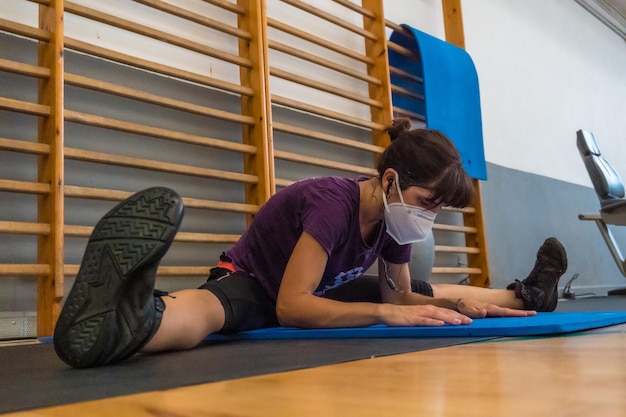 Junges kaukasisches mädchen mit gesichtsmaske, das sich nach abschluss der übung in einem fitnessstudio dehnt