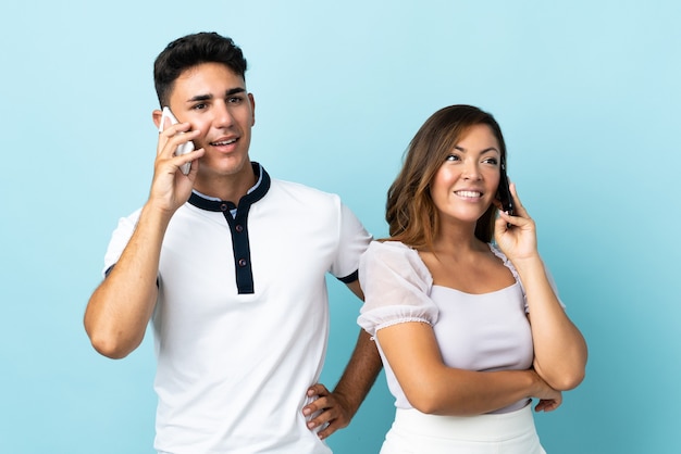 Junges kaukasisches Paar auf Blau, das mit Handy spricht