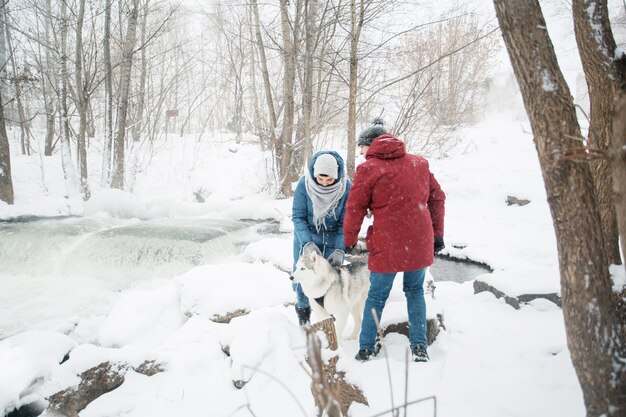 junges kaukasisches Paar, das mit Siberian Husky im Winter steht.