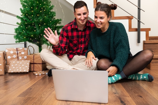 Junges kaukasisches Paar im Videoanruf feiert Weihnachten mit der Familie Winken hallo Holiday