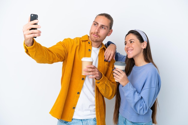 Junges kaukasisches Paar isoliert auf weißem Hintergrund, das ein Selfie mit dem Handy macht