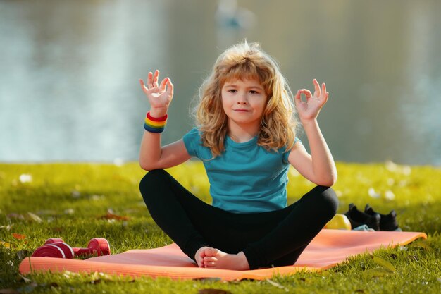 Junges Kind praktizieren Yoga im Freien Lotus Pose Yoga Harmonie und Meditation Konzept gesunder Lebensstil