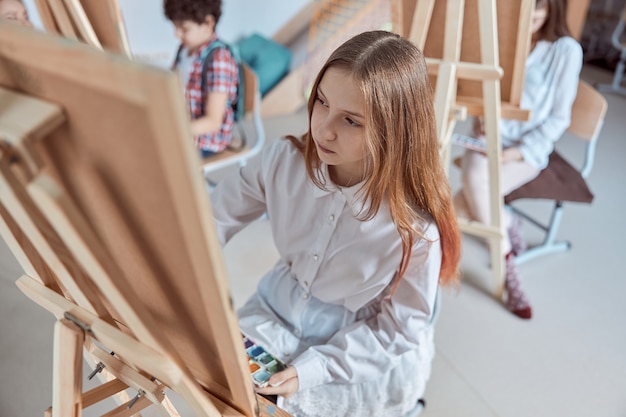 Junges kreatives mädchen zeichnet ein bild am hellen modernen klassenzimmer