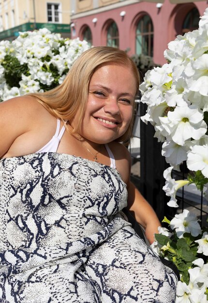 Foto junges lächelndes mädchen mit kurzer statur im rollstuhl posiert in der nähe von anhängern an einem sommertag porträt von