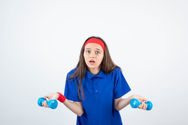 junges langhaariges Mädchen im Stirnbandtraining mit Hanteln.