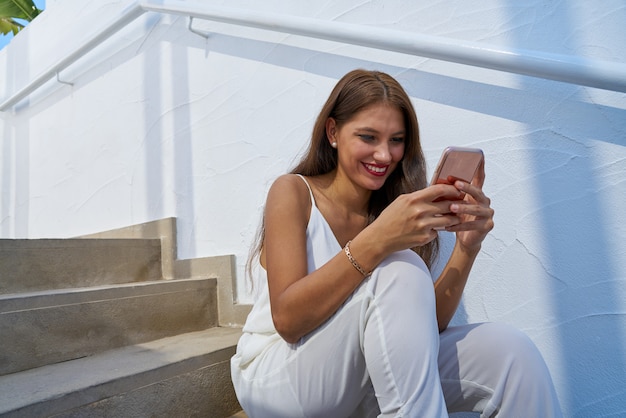 Junges lateinisches Frauenlesen smarphone im Freien