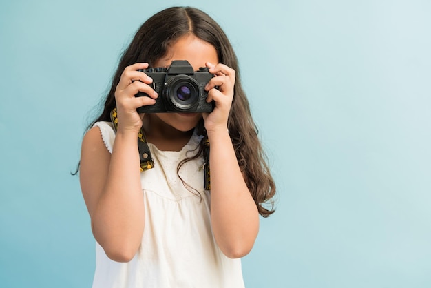 Junges lateinisches Mädchen, das mit Digitalkamera fotografiert, während es im Studio steht