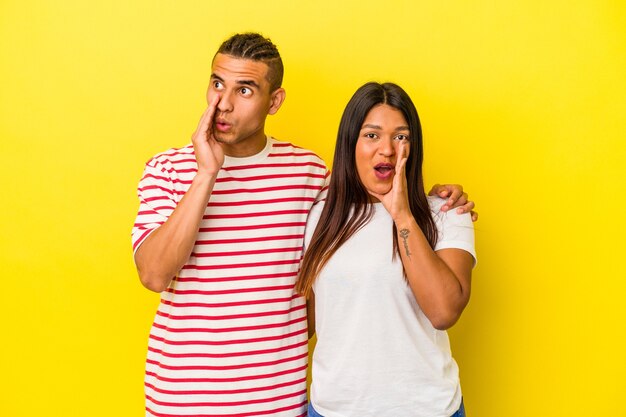 Junges lateinisches Paar, das auf gelbem Hintergrund isoliert ist, sagt eine geheime heiße Bremsnachricht und schaut beiseite