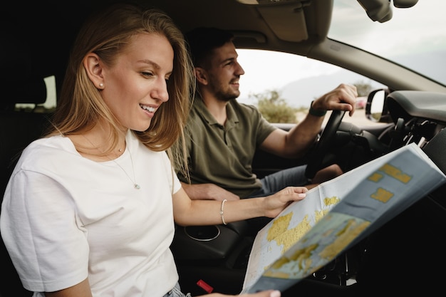 Junges Liebespaar auf einem Roadtrip mit Karte in einem Auto