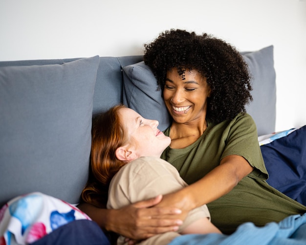 Junges Liebespaar, das sich im Bett umarmt, gleichgeschlechtliche Familie, lesbische Frauen beim zärtlichen Erwachen am Morgen