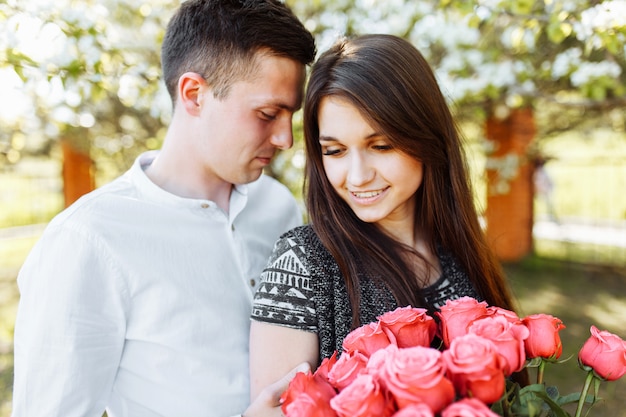 Junges Liebespaar in der Liebe, Frau, die Blumen hält, glücklich und genießt die schöne Natur