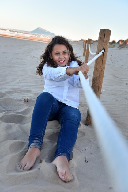 Junges Mädchen am Strand, das mit einem Seil spielt