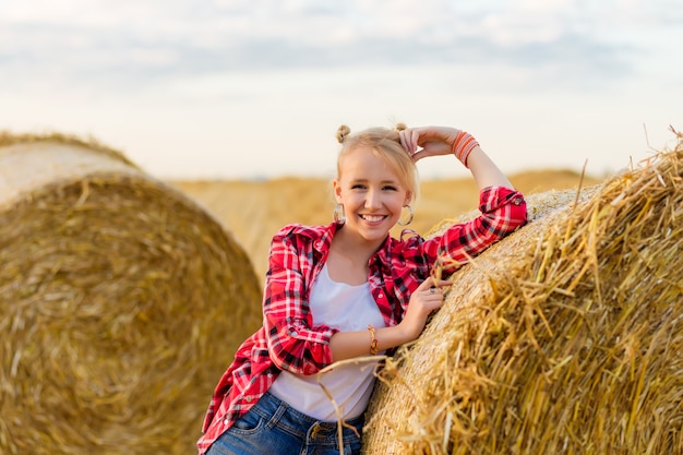 Junges Mädchen auf Strohgarben in einem Feld.