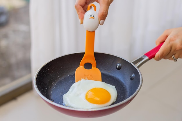 Junges Mädchen bereitet zum Frühstück schöne Eier in der Pfanne zu