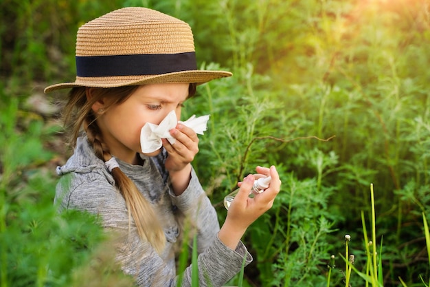 Junges Mädchen bläst die Nase mit Nasensprays und anderen Medikamenten im Vordergrund Allergiekonzept