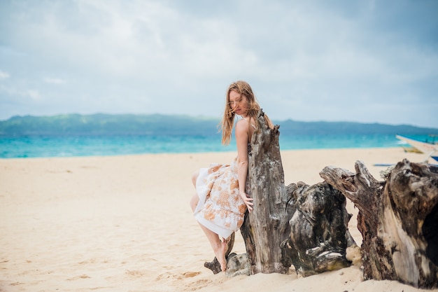 Junges Mädchen, das auf einem alten Baum am Strand von Boracay sitzt