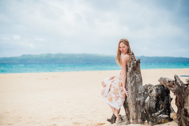 Junges Mädchen, das auf einem alten Baum am Strand von Boracay sitzt