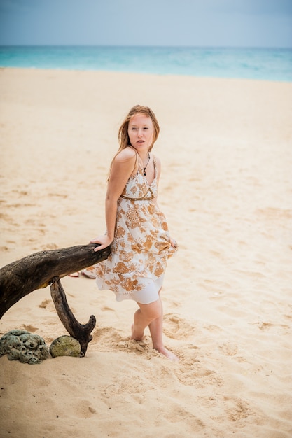 Junges Mädchen, das auf einem alten Baum am Strand von Boracay sitzt