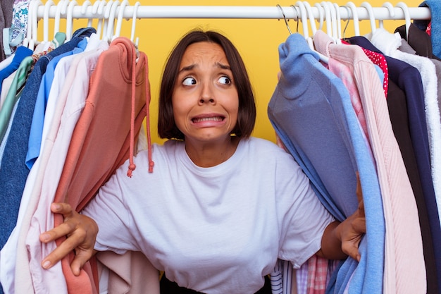 Junges Mädchen, das aus einer Garderobe herauskommt, die auf gelbem Hintergrund lokalisiert wird